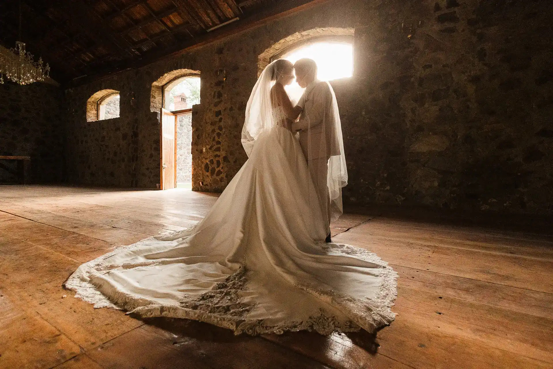Novios abrazados frente a ventana en hacienda colonial mexicana de piedra, fotografía editorial de boda Salicatus