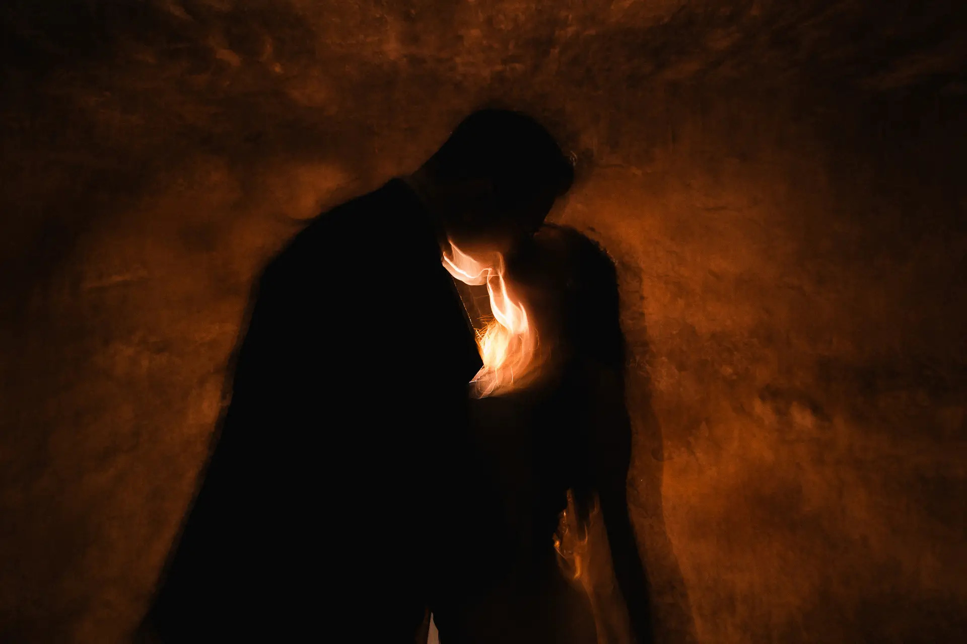 Silueta de novios abrazados con luz de bengala dorada sobre muro texturizado, fotografía artística de boda Salicatus