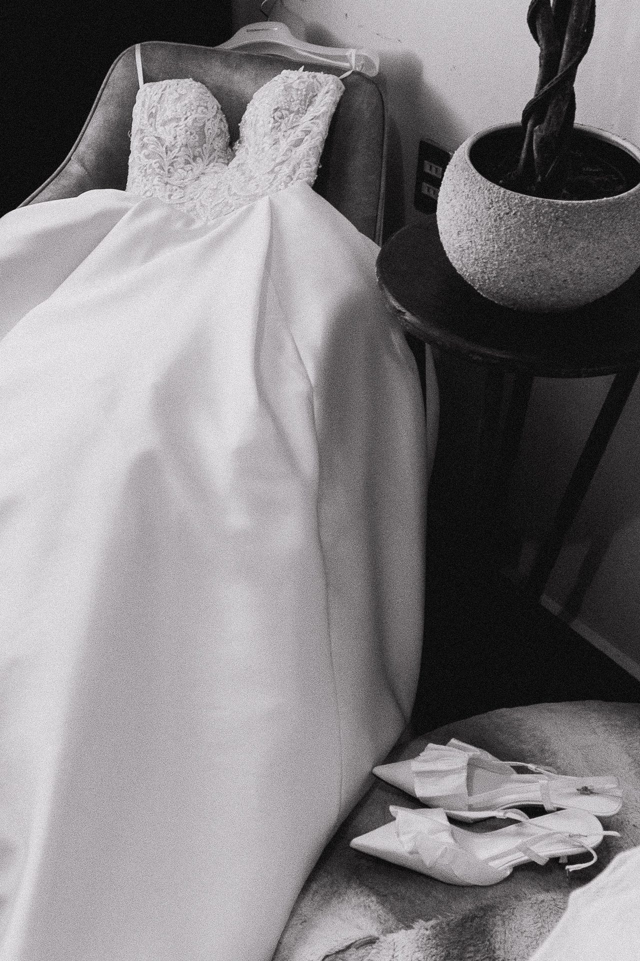 Vestido de novia con corpiño de encaje sobre silla de terciopelo, fotografía editorial en blanco y negro de detalles previos a la boda — Salicatus