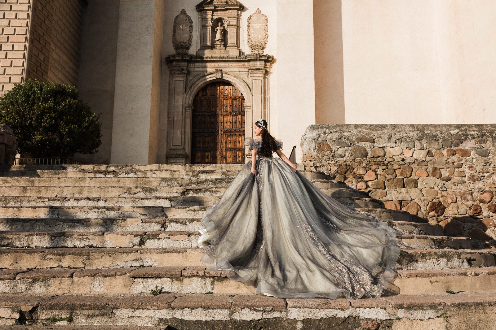 Quinceañera con vestido gris de tul y bordados sobre escaleras de iglesia colonial mexicana al atardecer, sesión Glam editorial — Salicatus